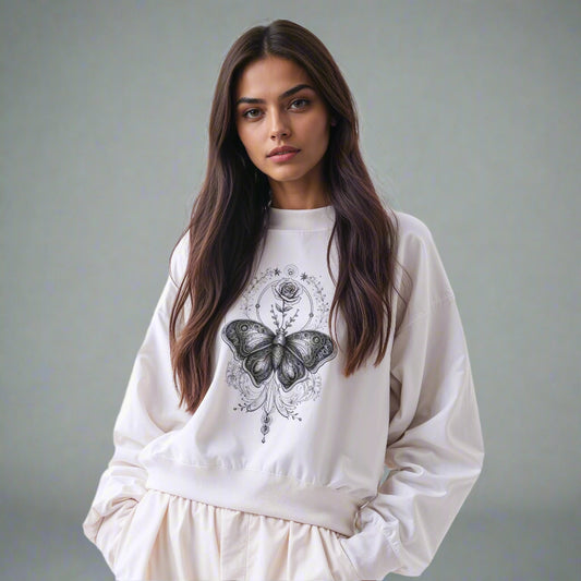Ornamental butterfly and rose graphic sweatshirt in off-white, shown on a female model for style and fit reference. Black and white artistic print.