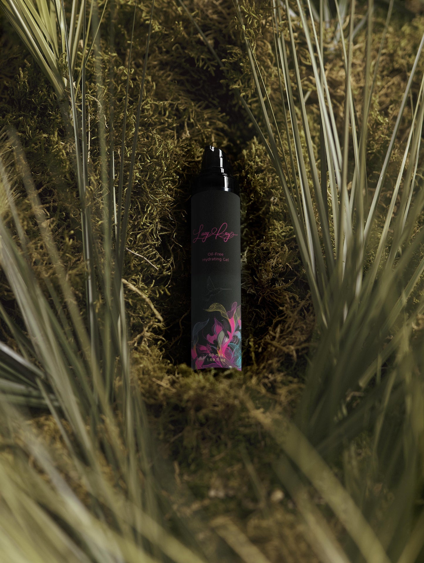 Black bottle with floral design on a bed of grass and moss. Lucy Kay cosmetics