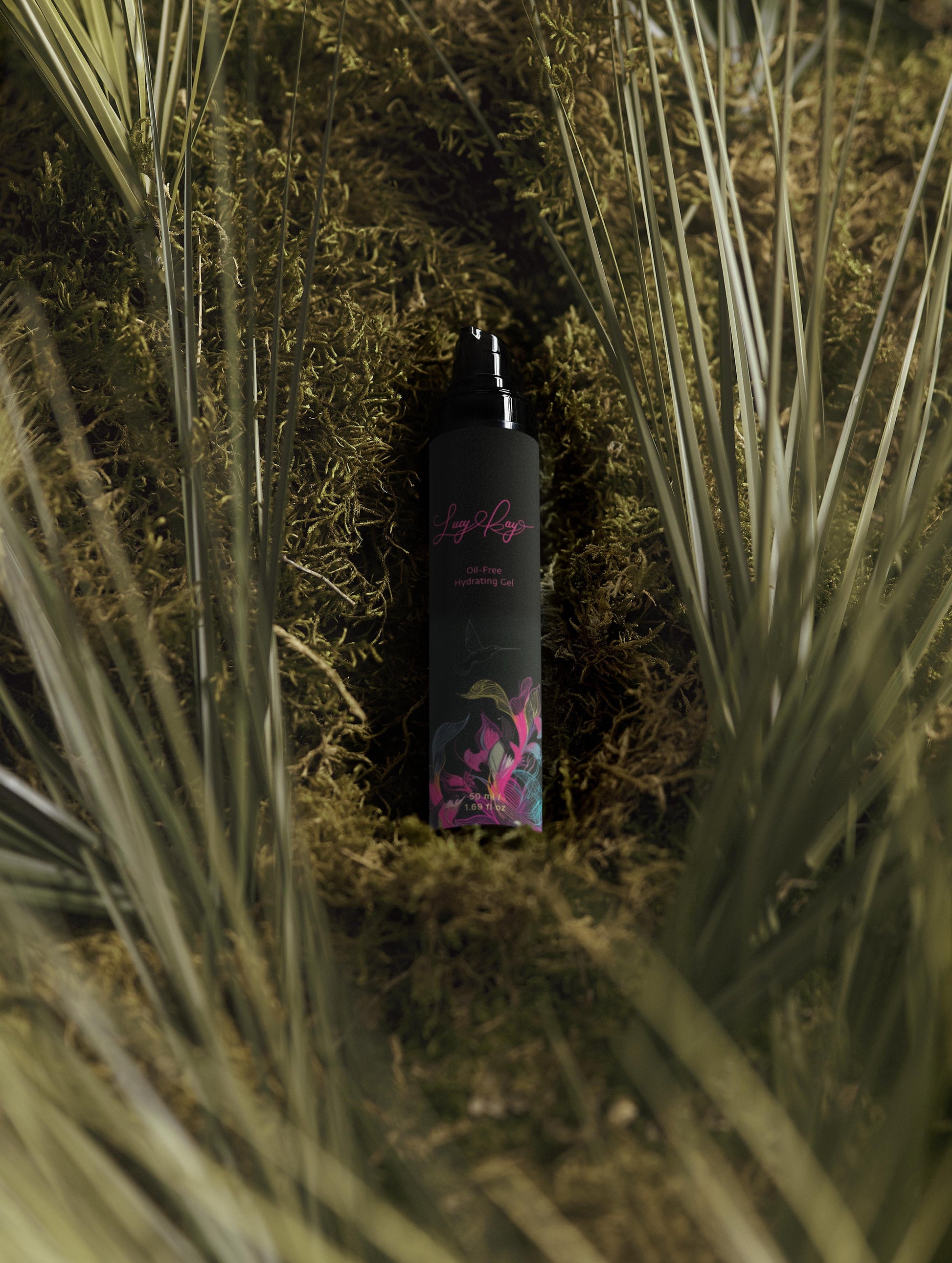 Black bottle with floral design on a bed of grass and moss. Lucy Kay cosmetics