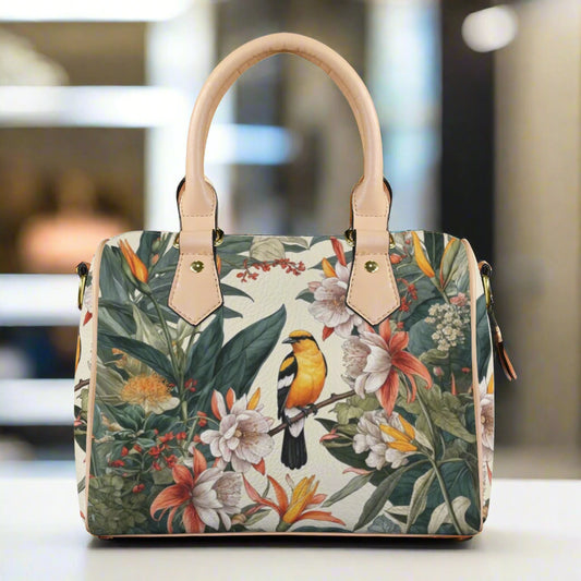 Front view of a PU leather satchel handbag featuring a detailed tropical floral and yellow bird print. The bag has sturdy light tan top handles and includes a removable, adjustable shoulder strap.